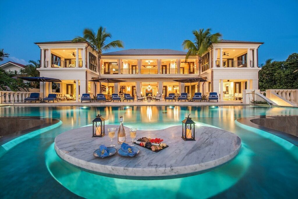 A stunning view of a luxurious villa with a grand entrance, surrounded by lush greenery.